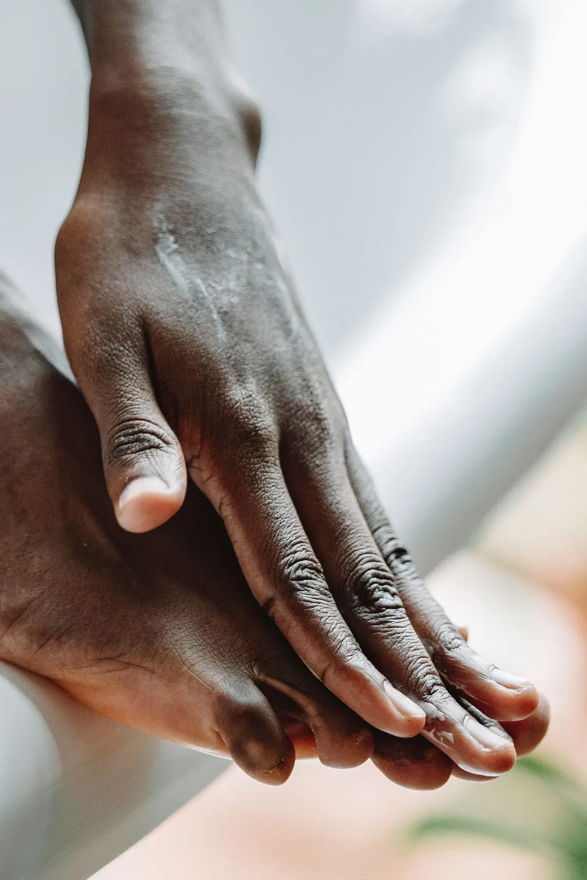 Hands applying skincare cream to a foot during a self-care routine.