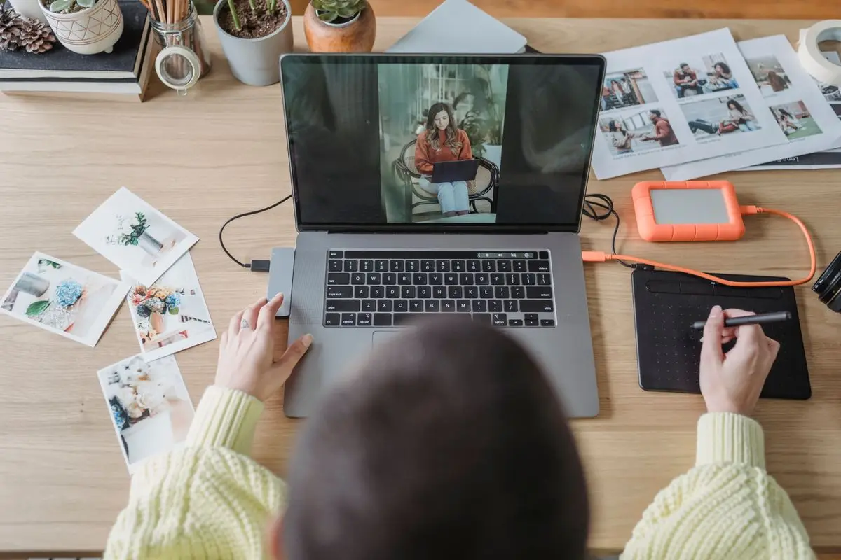 A person editing photos on a laptop with a graphics tablet.