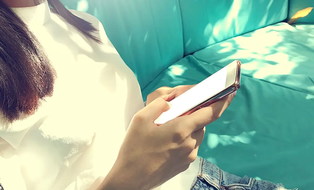 Una persona si rilassa sul divano mentre naviga sullo smartphone.