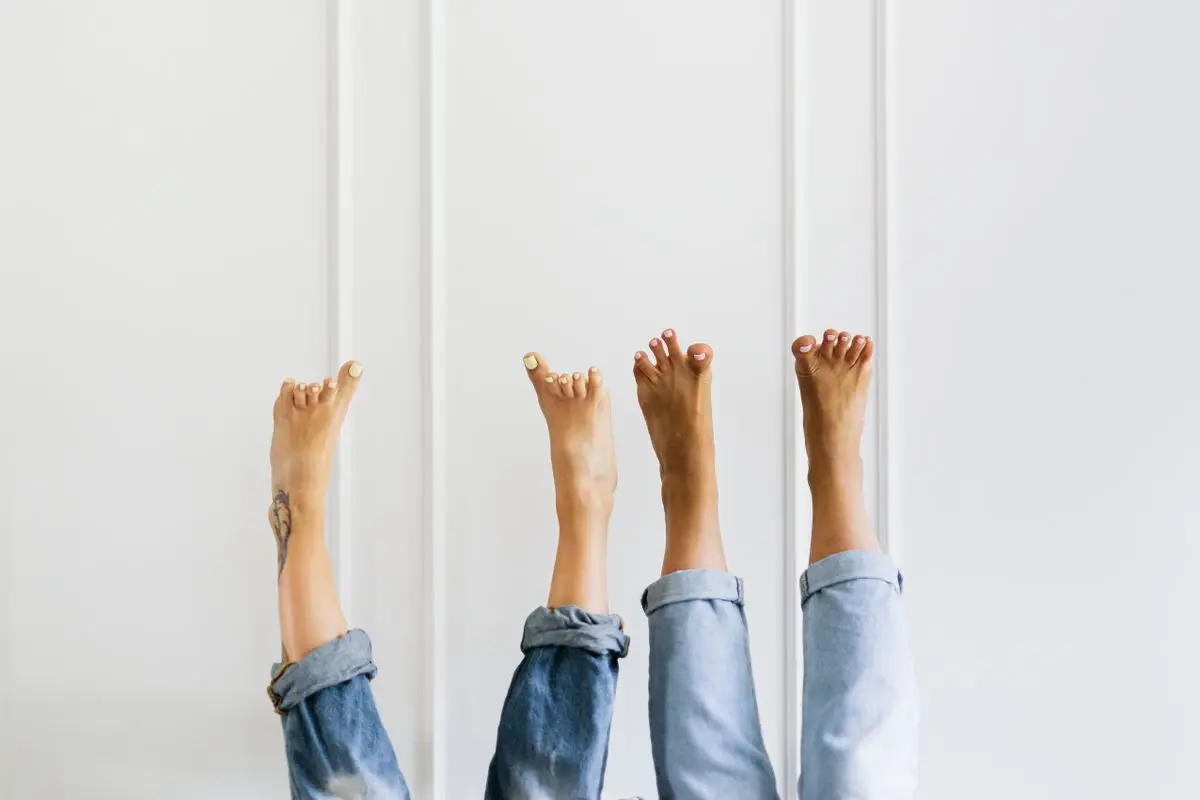 Bare feet playfully raised against a plain white wall.