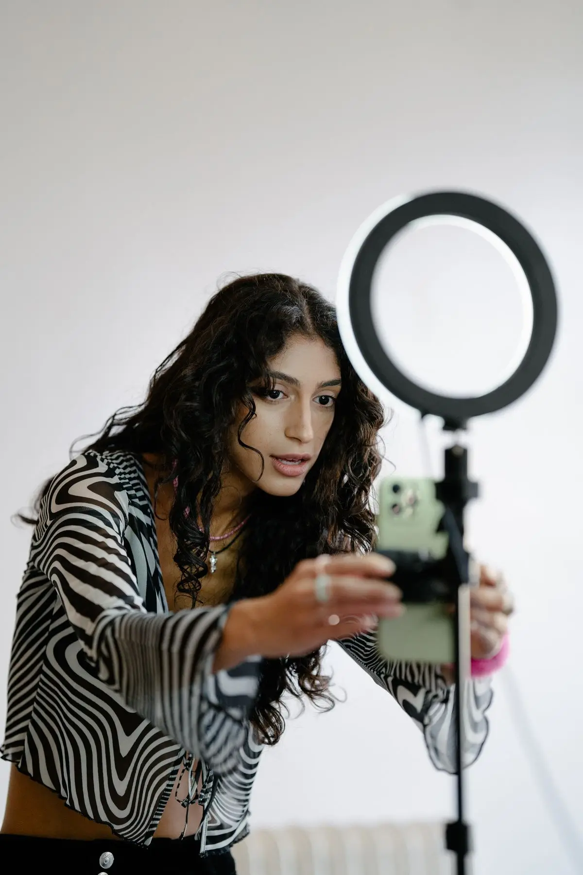 Una persona ajustando un smartphone en un trípode con aro de luz.